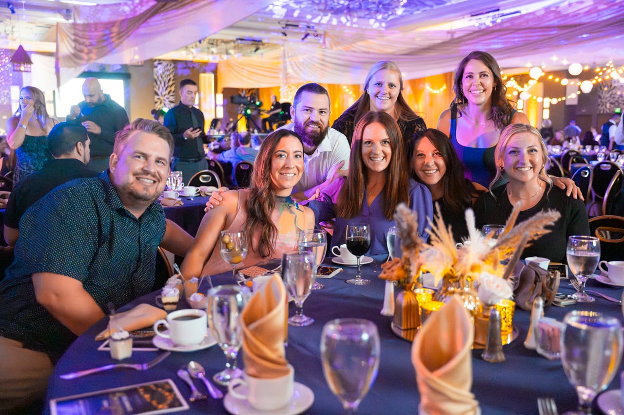 Eight Renown friends leaning in together at their table