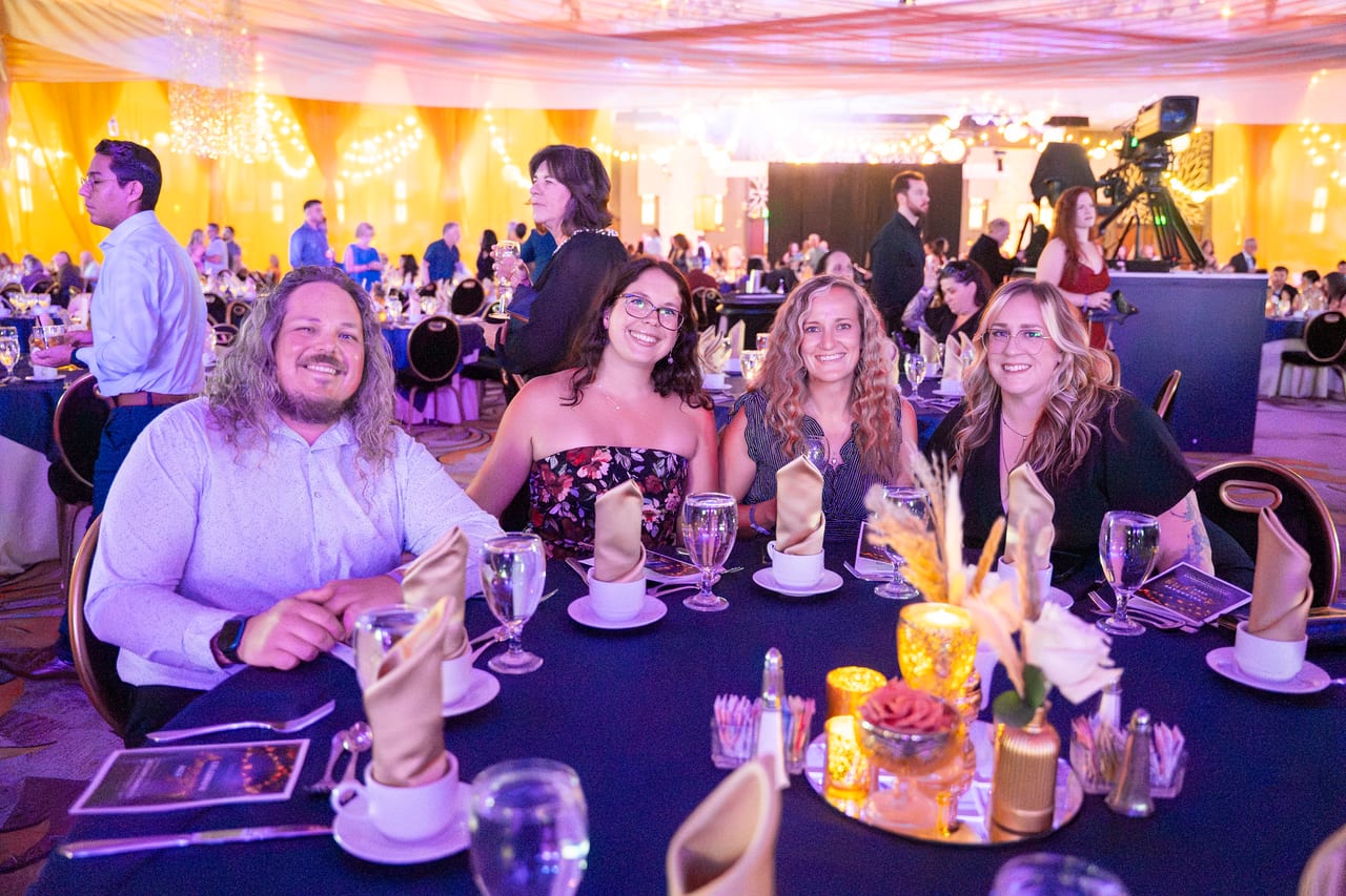 Five Renown tablemates leaning in for a photo at their candlelit table