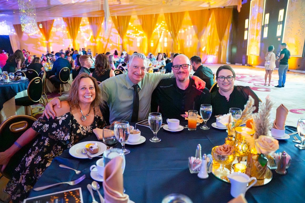 Five Renown tablemates smiling together around their candlelit table