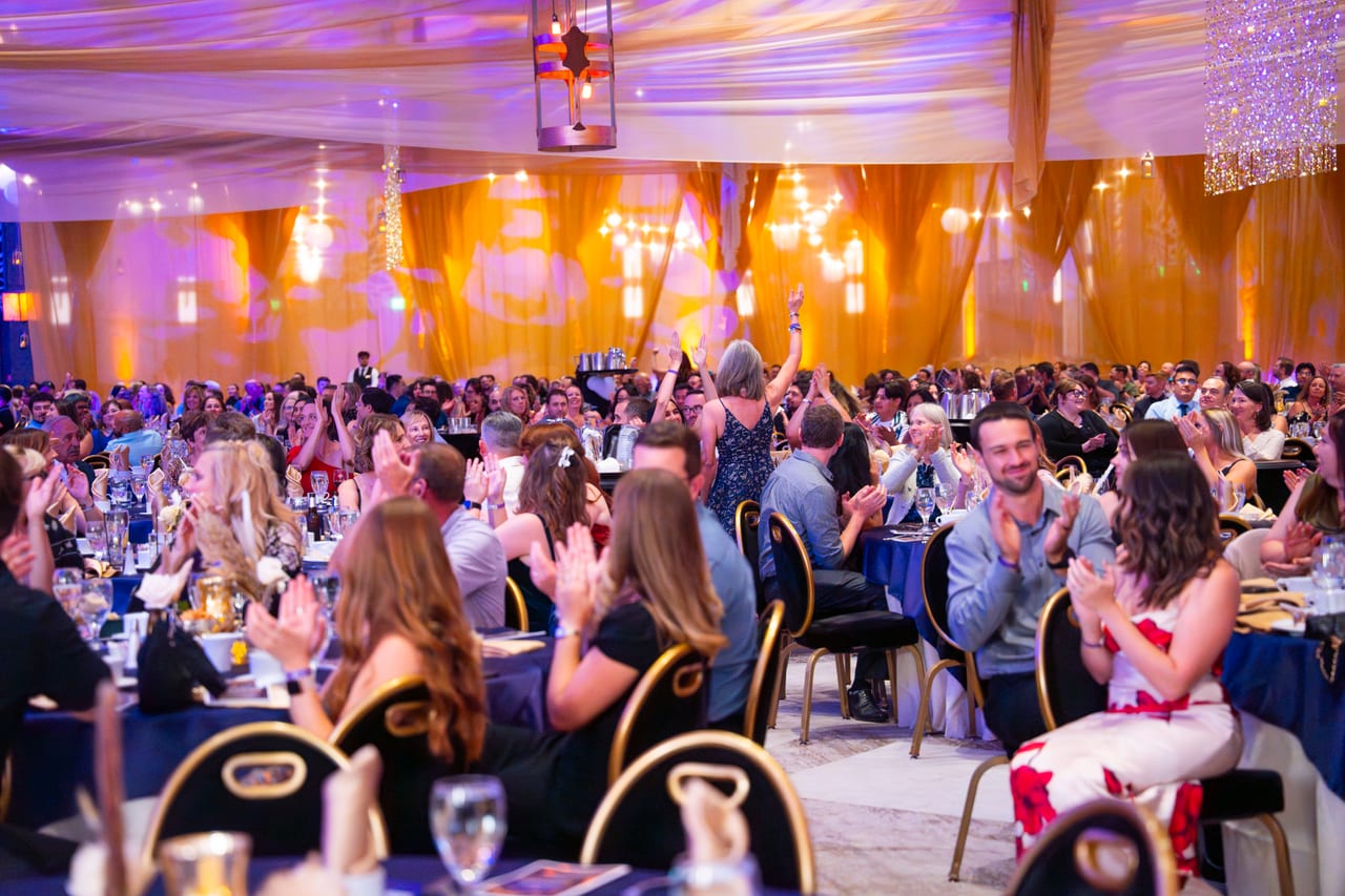 Renown tables clapping and cheering under the gold drapes