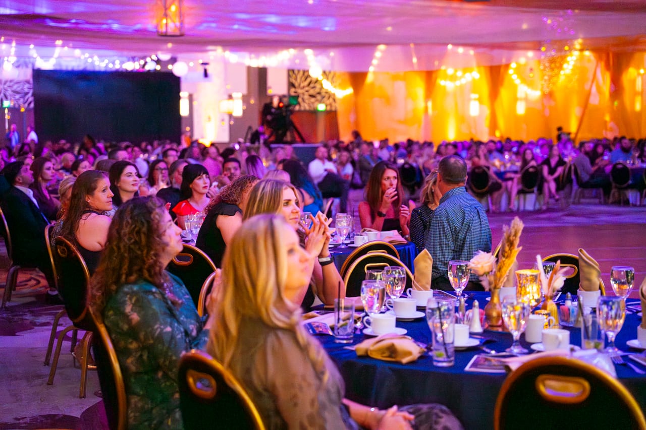 Renown guests at their tables turning to watch the stage