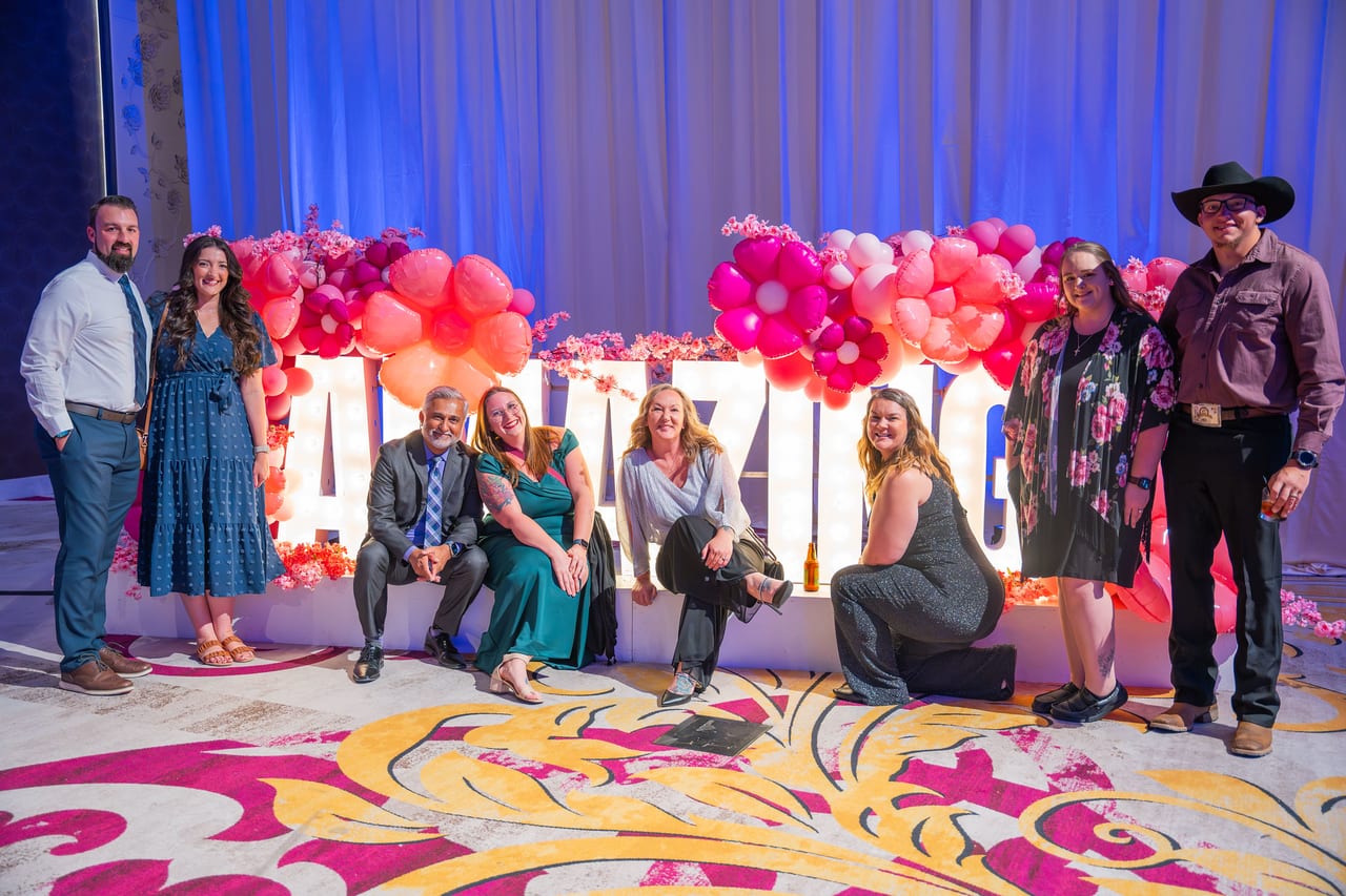 A Renown team gathered around the AMAZING letters, sitting, kneeling and standing