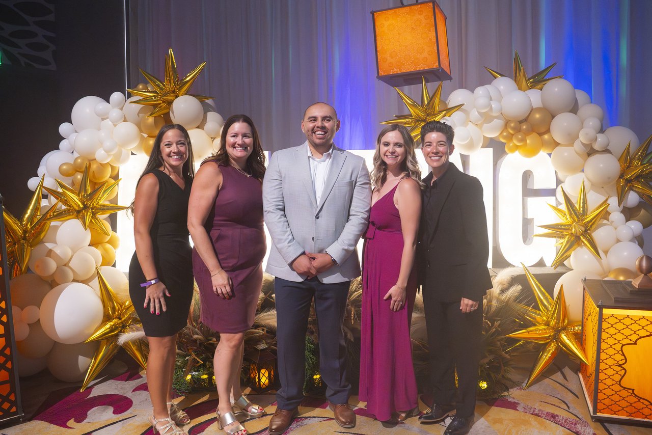 A Renown team posing under the gold star balloon arch