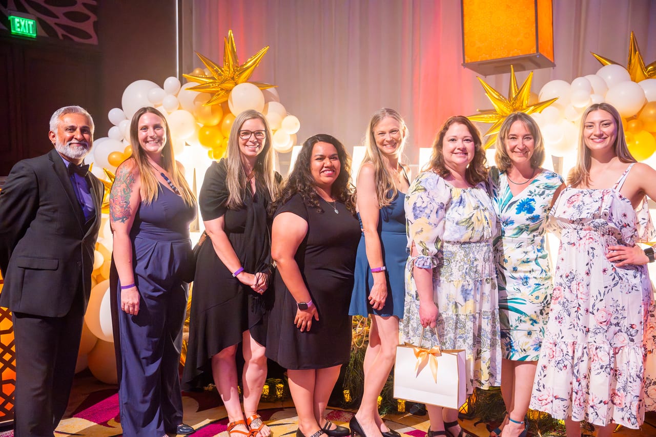 A Renown team lined up in front of the gold star balloon wall