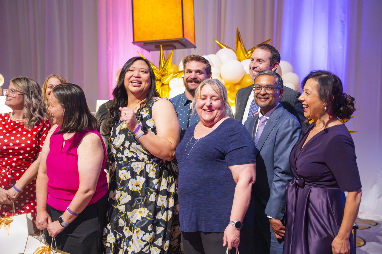 A Renown team laughing together at the gold balloon arch