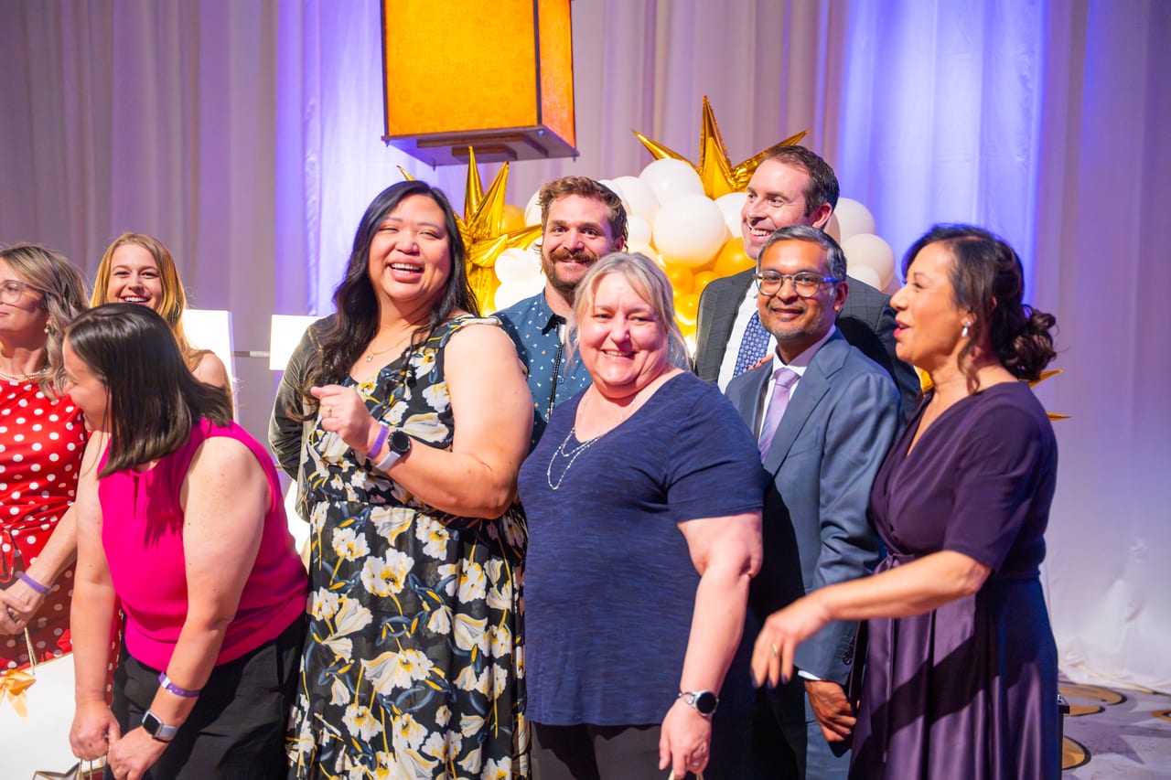 A Renown team laughing together in front of the gold balloon wall