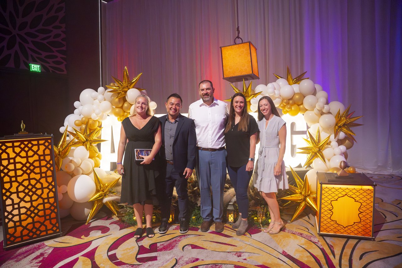 Five Renown coworkers posing at the gold balloon arch