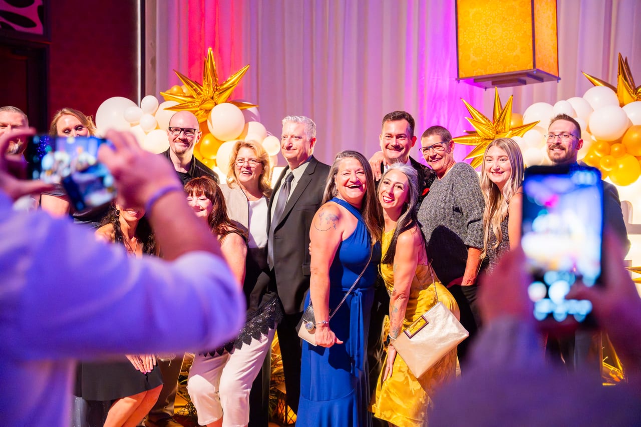 A Renown team posing at the balloon wall as friends snap photos on their phones