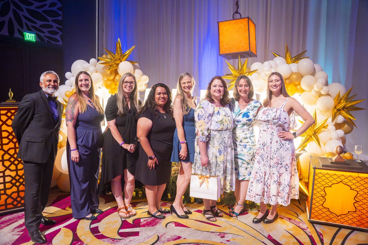 A Renown team posing together at the gold balloon arch