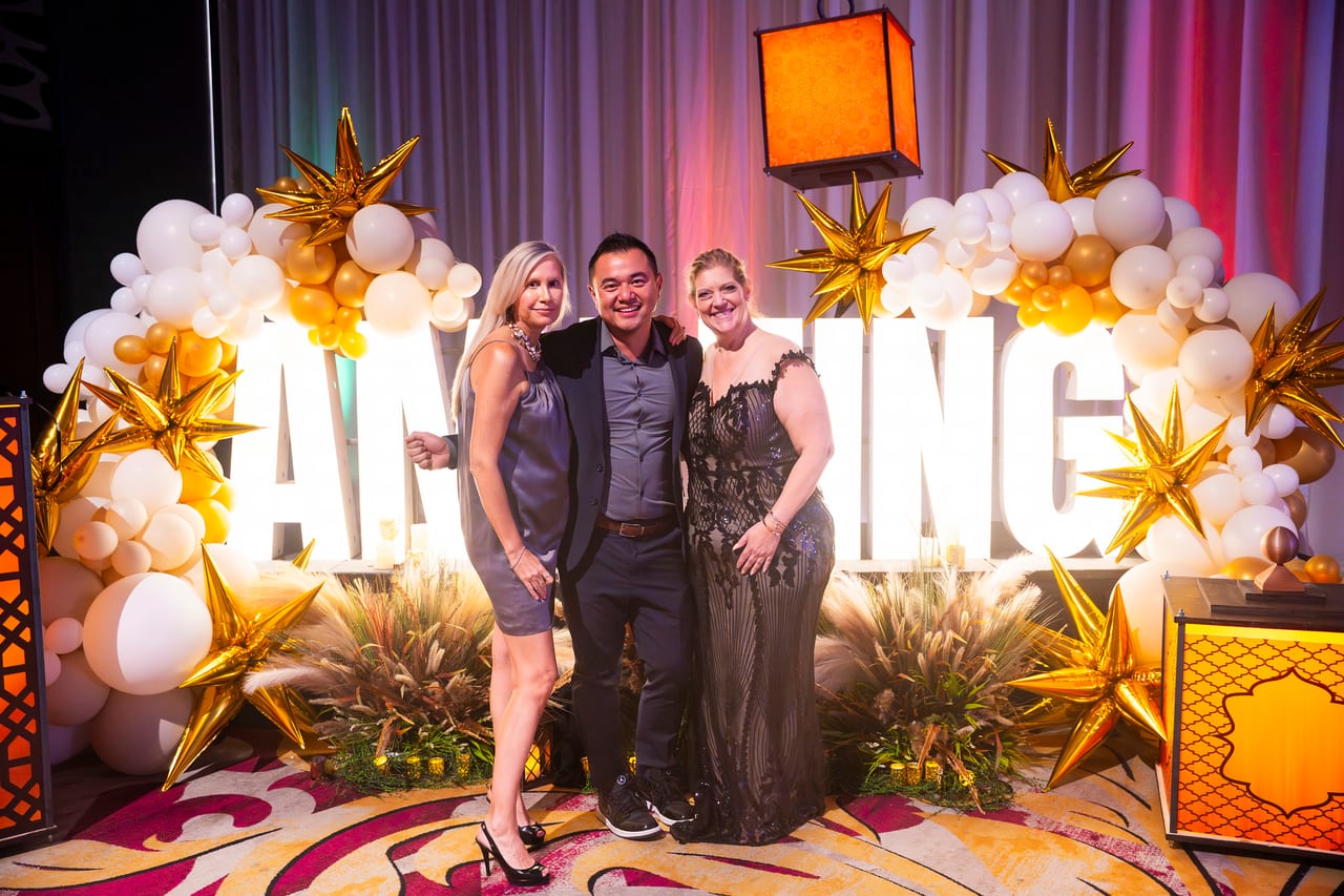 Three Renown coworkers posing under the gold star AMAZING arch