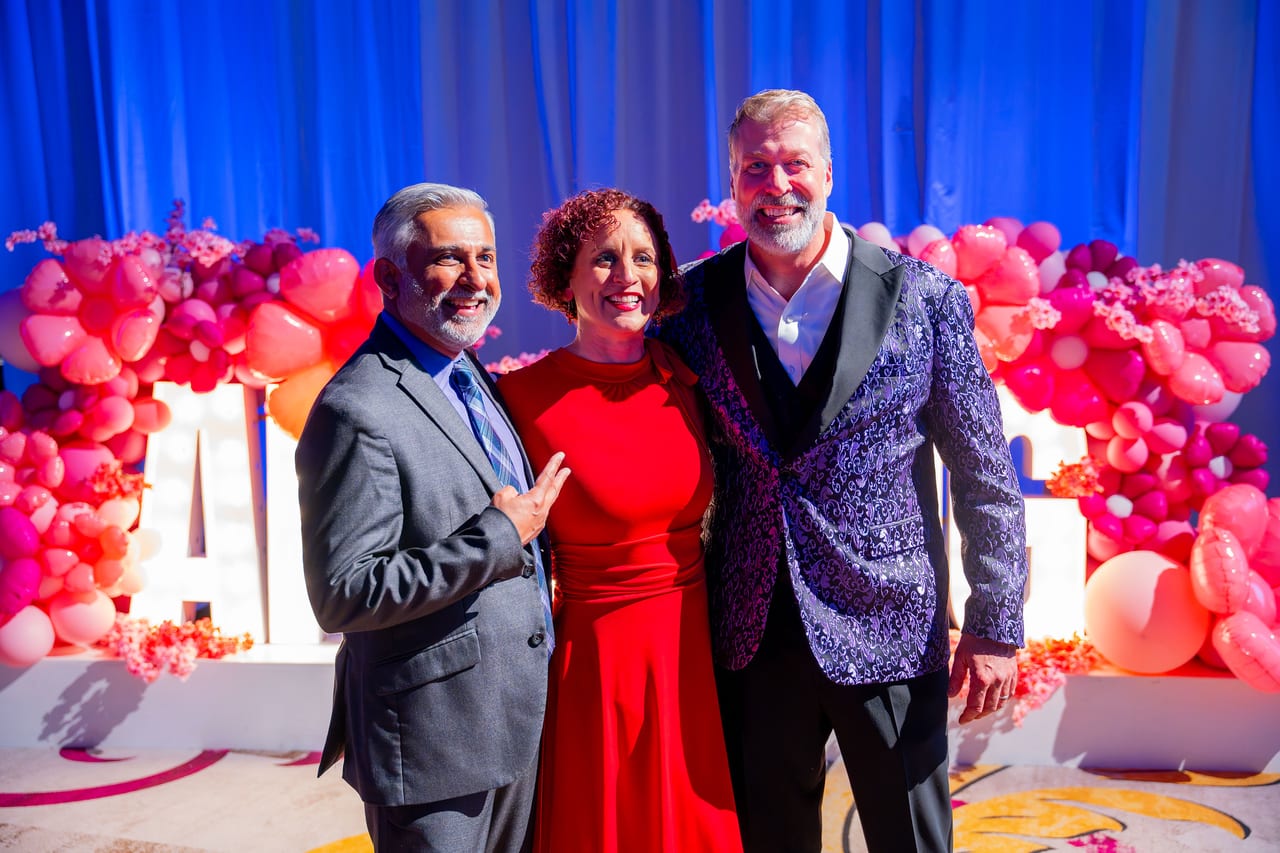 Three Renown guests posing at the balloon garland and lit letters