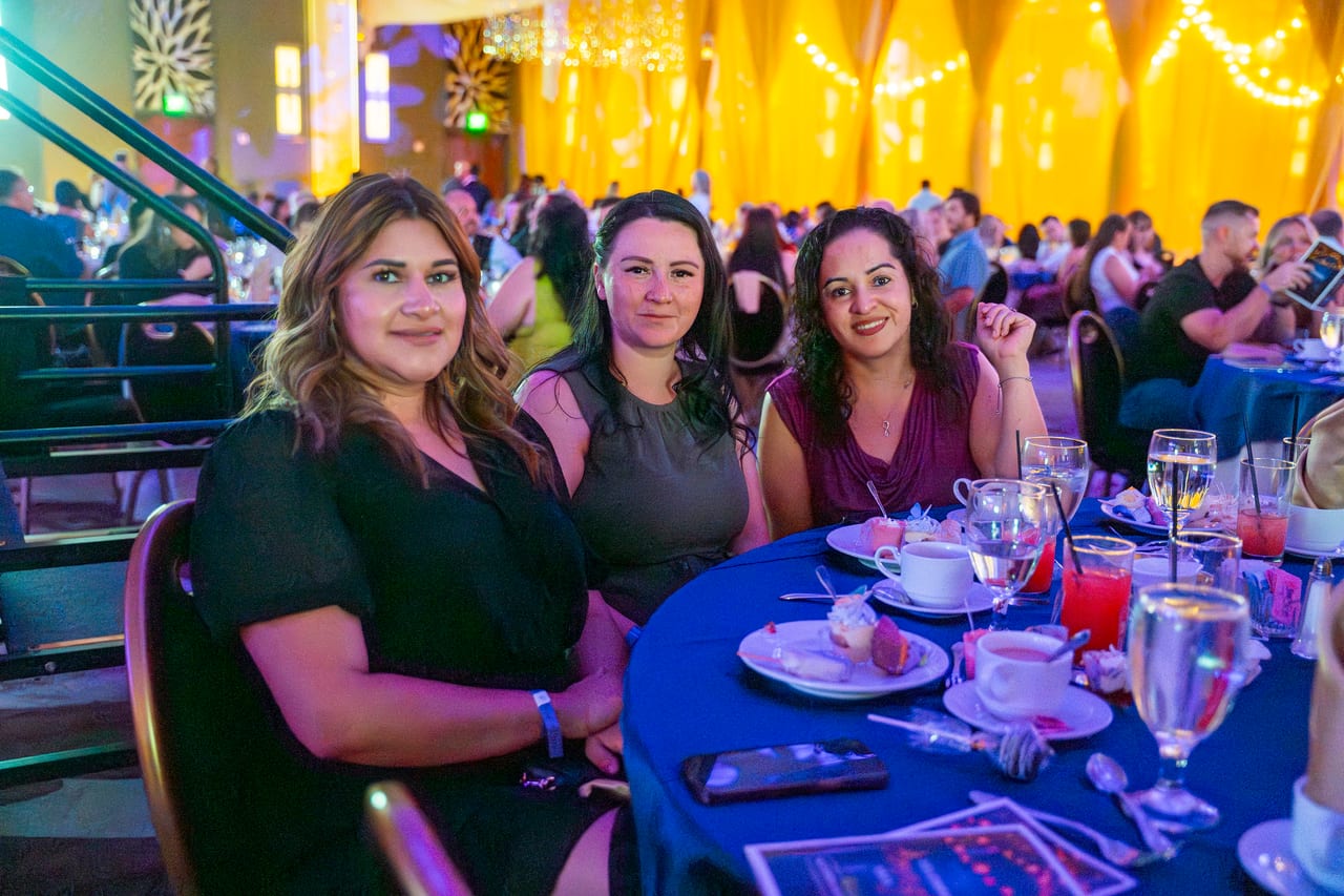 Three Renown friends smiling at their table under the gold light
