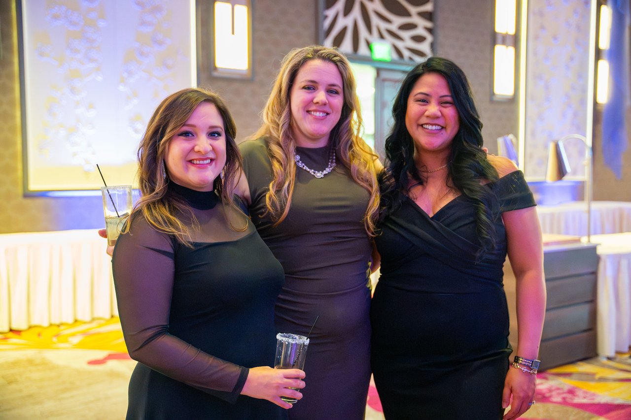 Three Renown friends in black dresses posing together in the ballroom