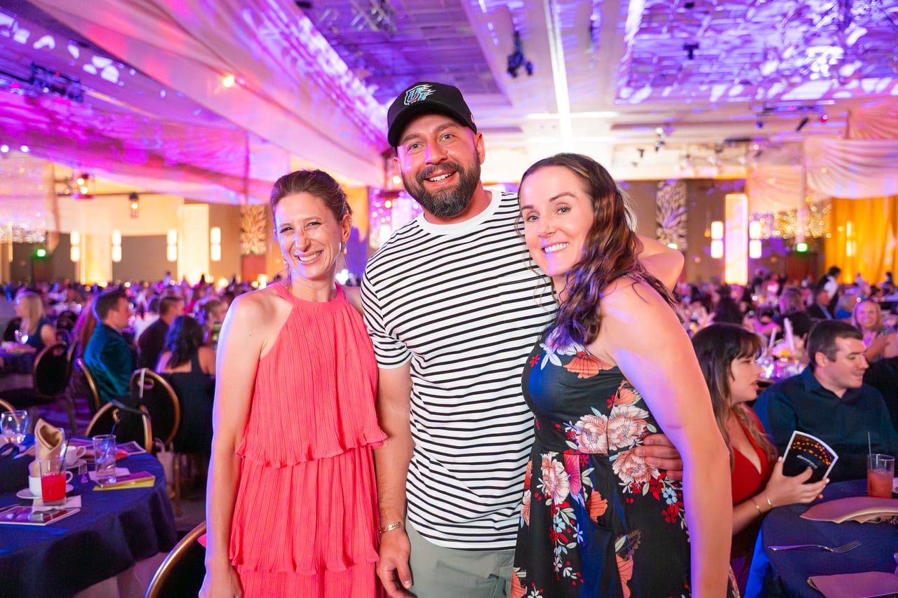 Three Renown friends smiling in the middle of the full ballroom