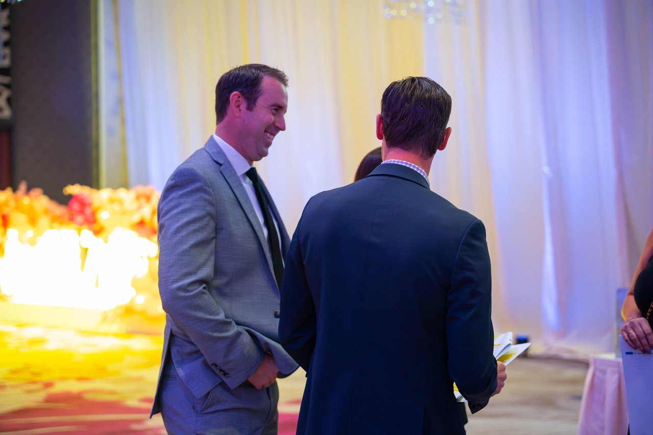 Two Renown coworkers in suits laughing together beside the stage