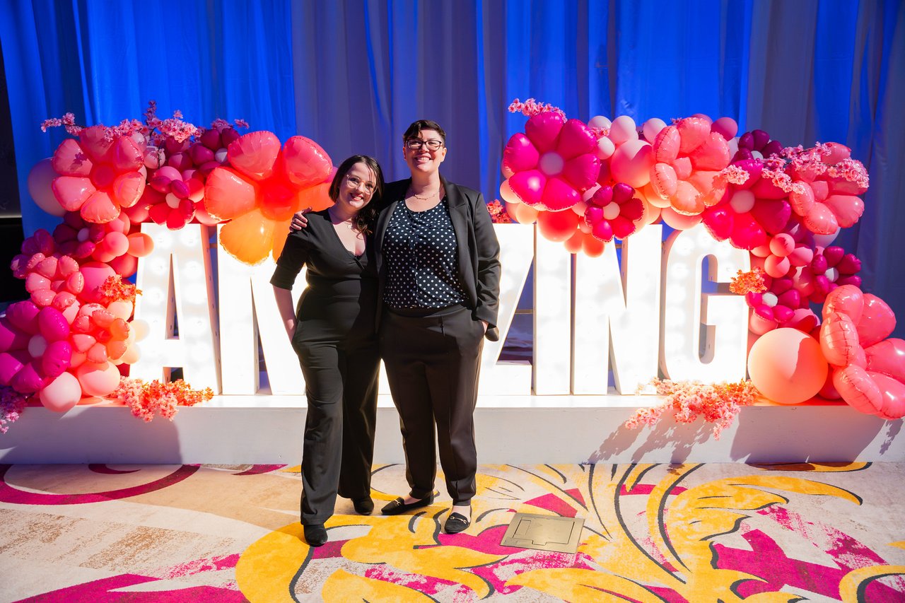 Two Renown friends in black posing at the Amazing sign