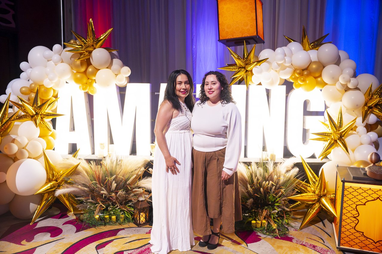 Two Renown friends posing at the gold balloon arch