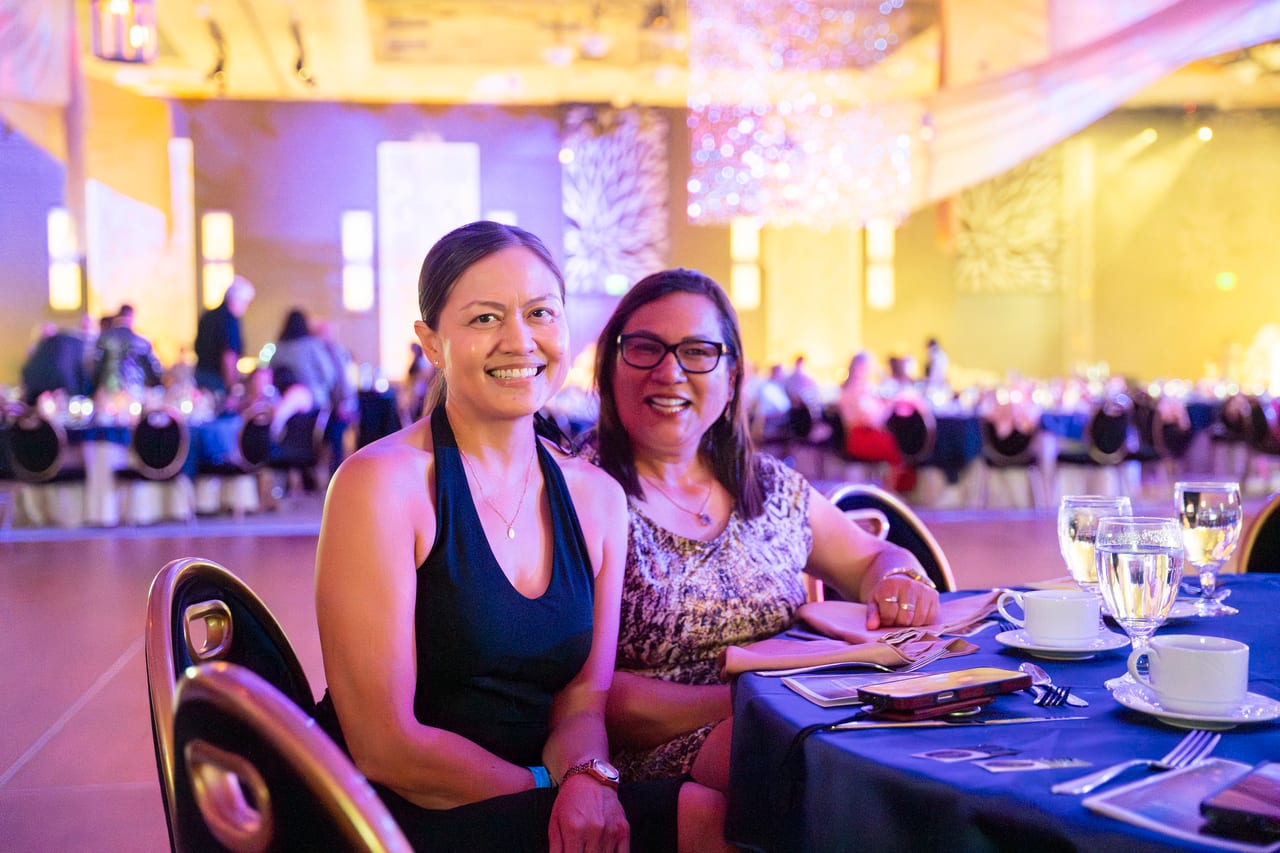 Two Renown friends smiling at their table under the chandeliers