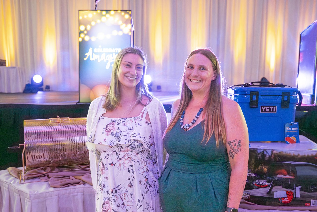 Two Renown friends posing beside the raffle prizes