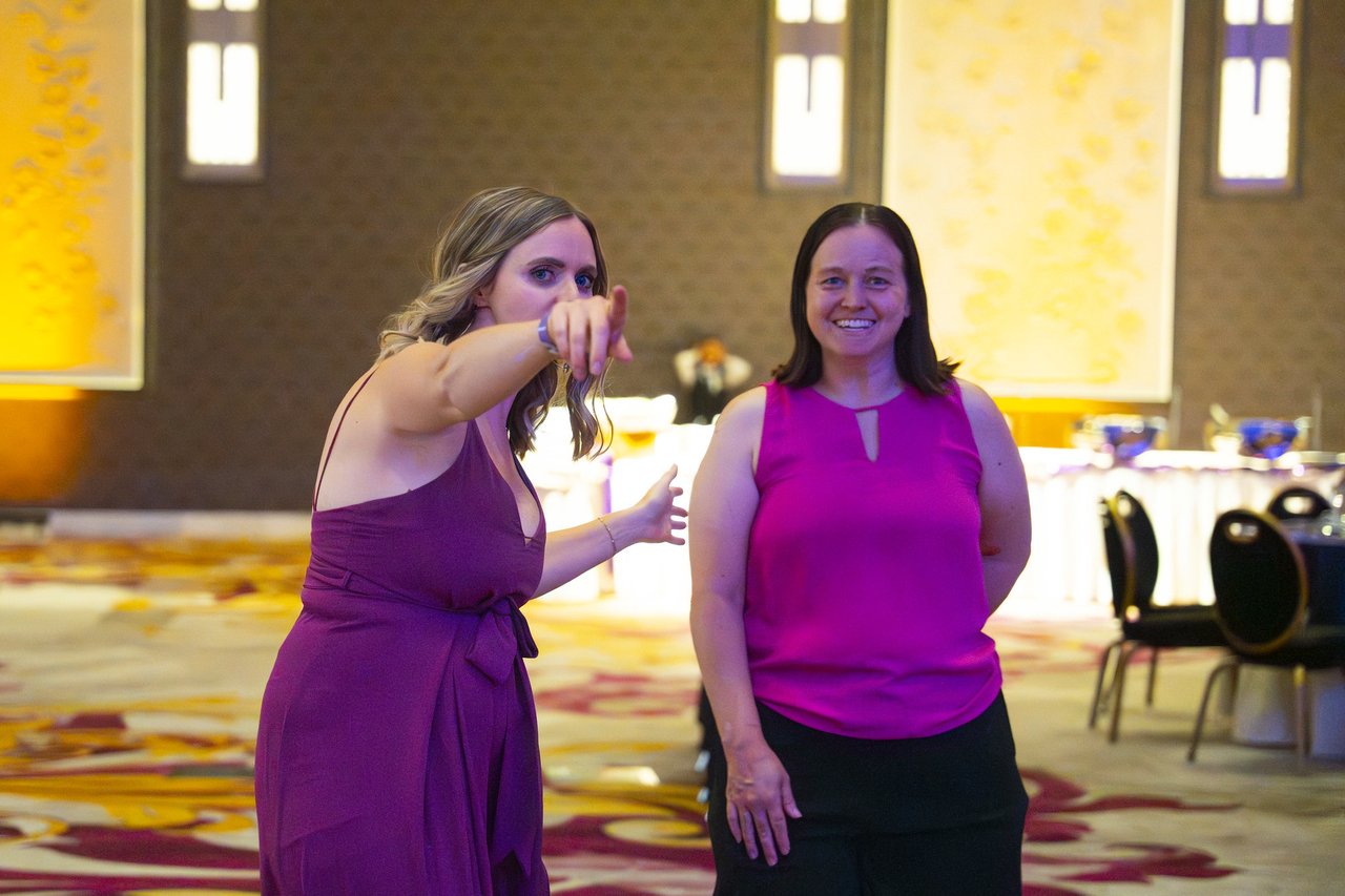 Two Renown friends pointing across the ballroom