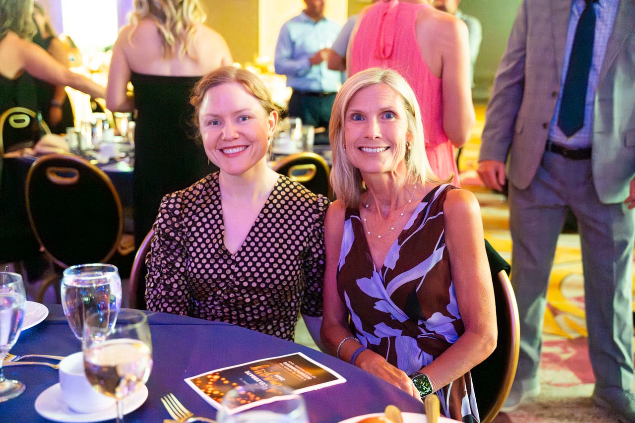 Two Renown friends smiling side by side at their table