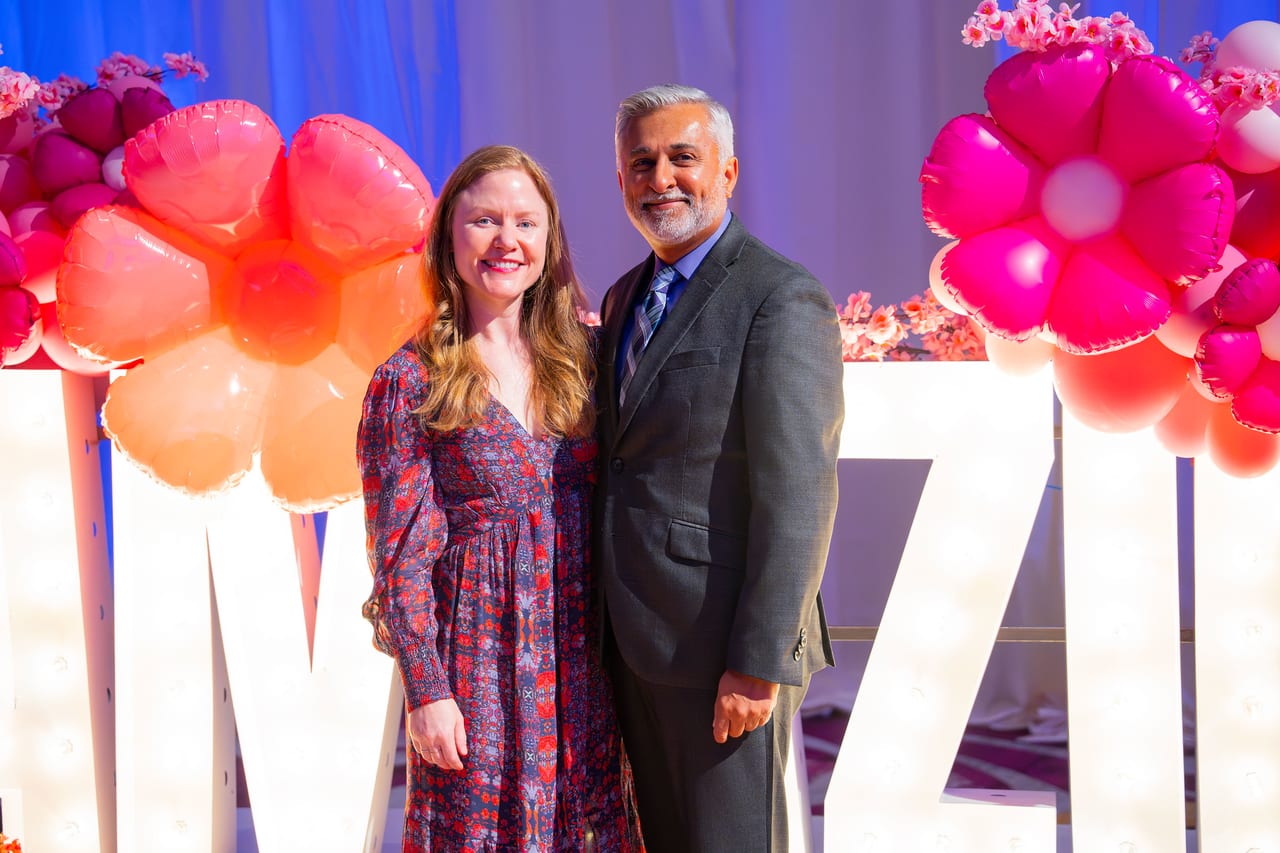 Two Renown guests posing together at the lit letters and balloon flowers