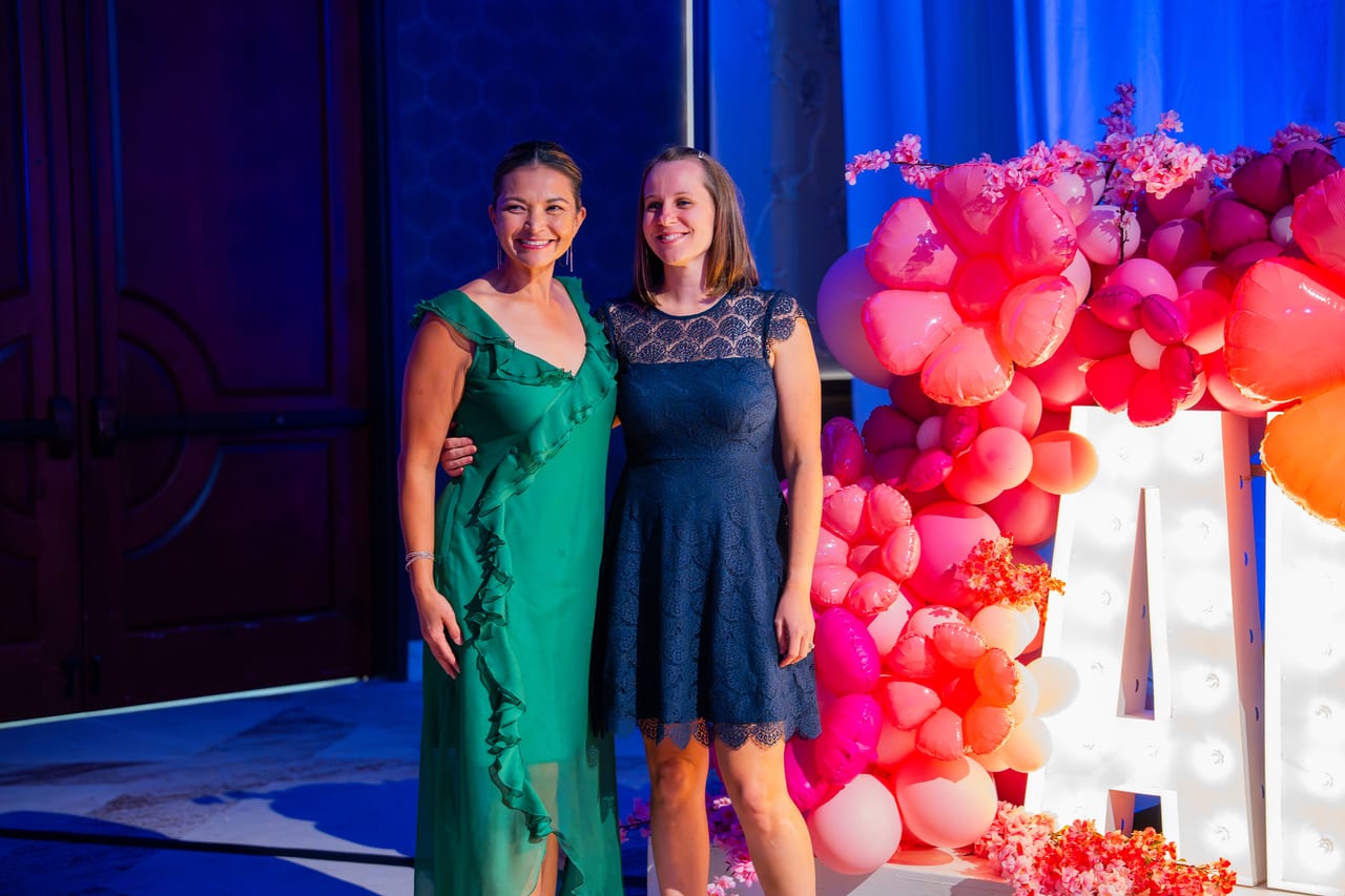 Two Renown honorees posing beside the balloon garland and lit letters