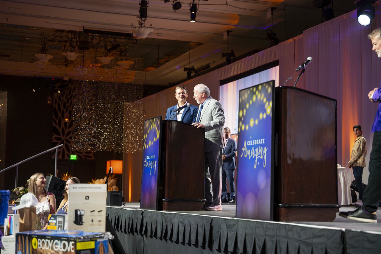Two Renown leaders at the podium above the prize table
