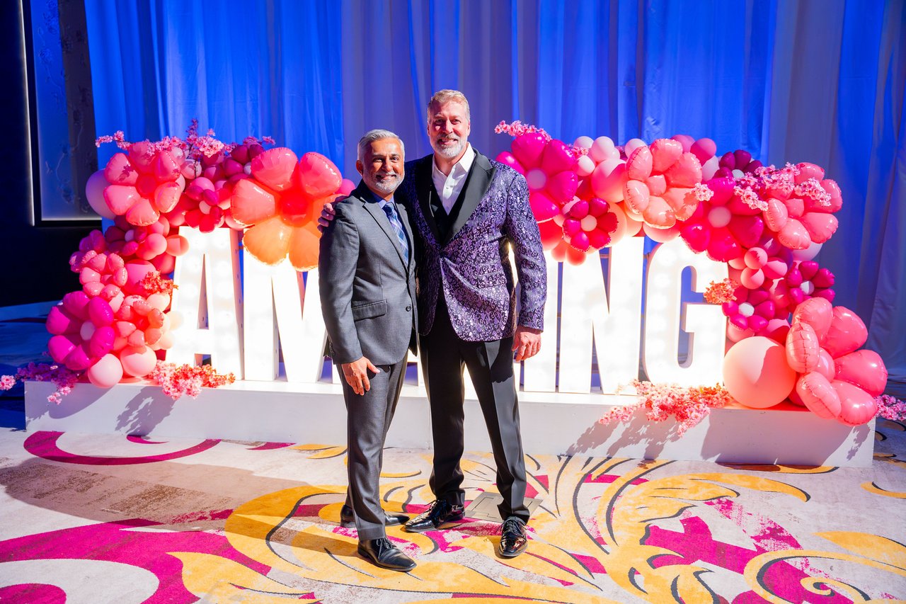 Two Renown coworkers in suits posing at the Amazing sign