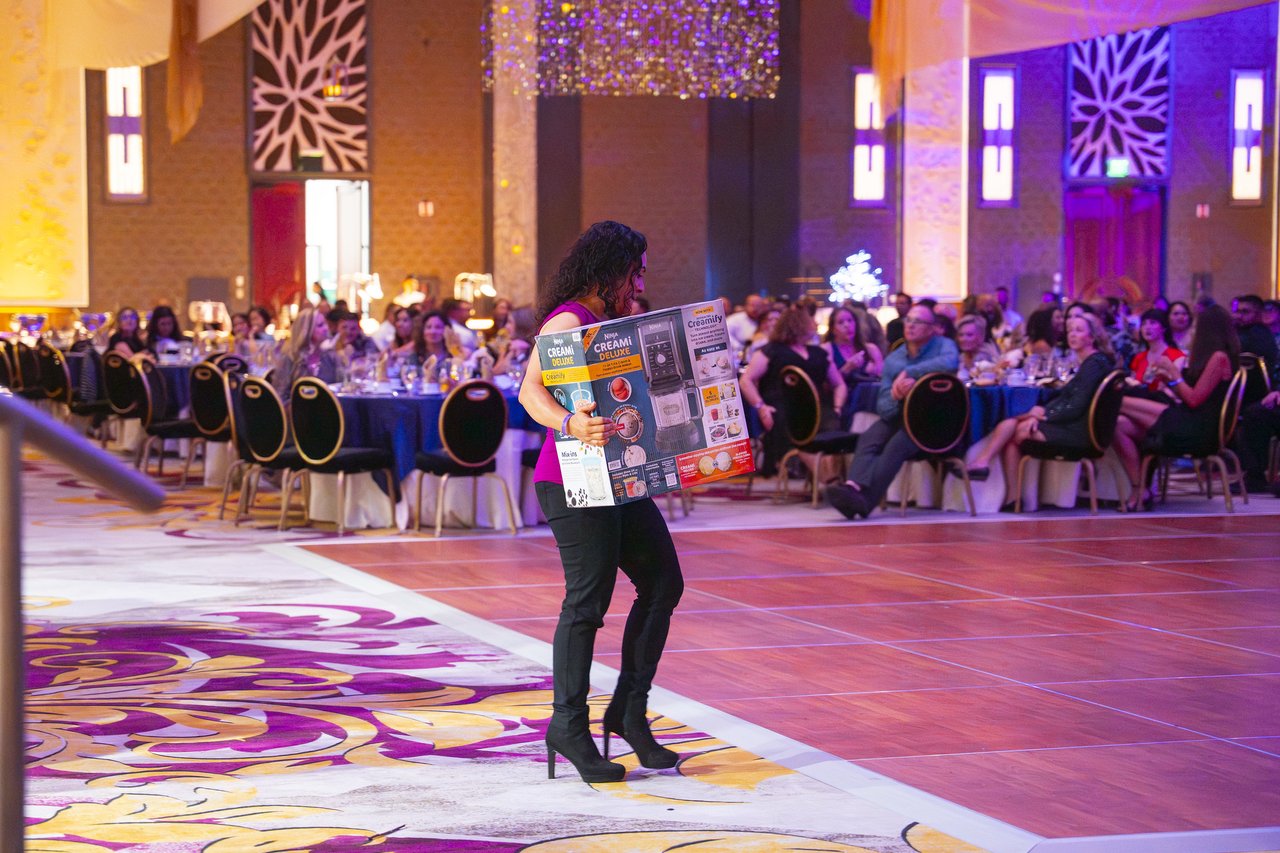 A Renown guest carrying a big prize box across the dance floor
