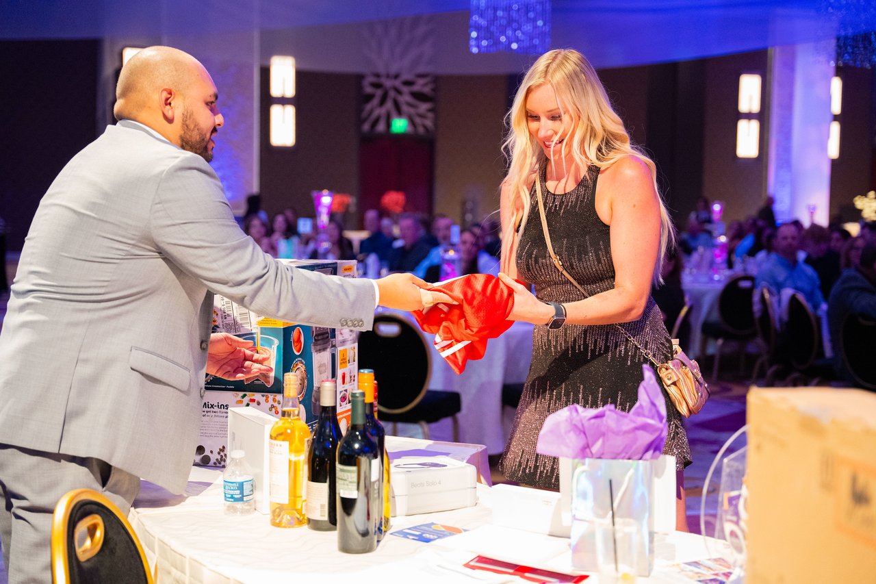 A smiling winner taking her red gift bag at the prize table