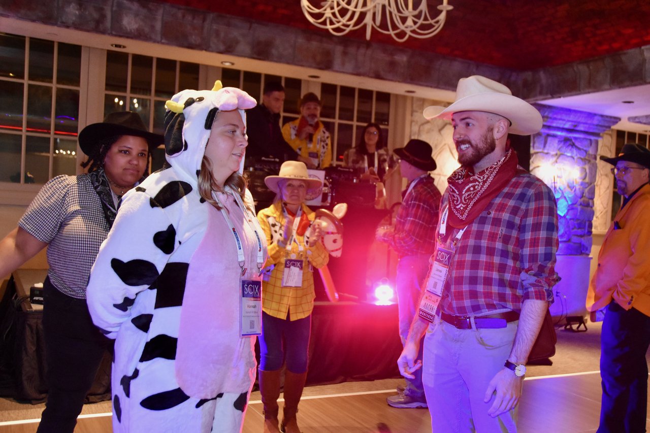 A cow costume and a cowboy on the SciX Gala dance floor
