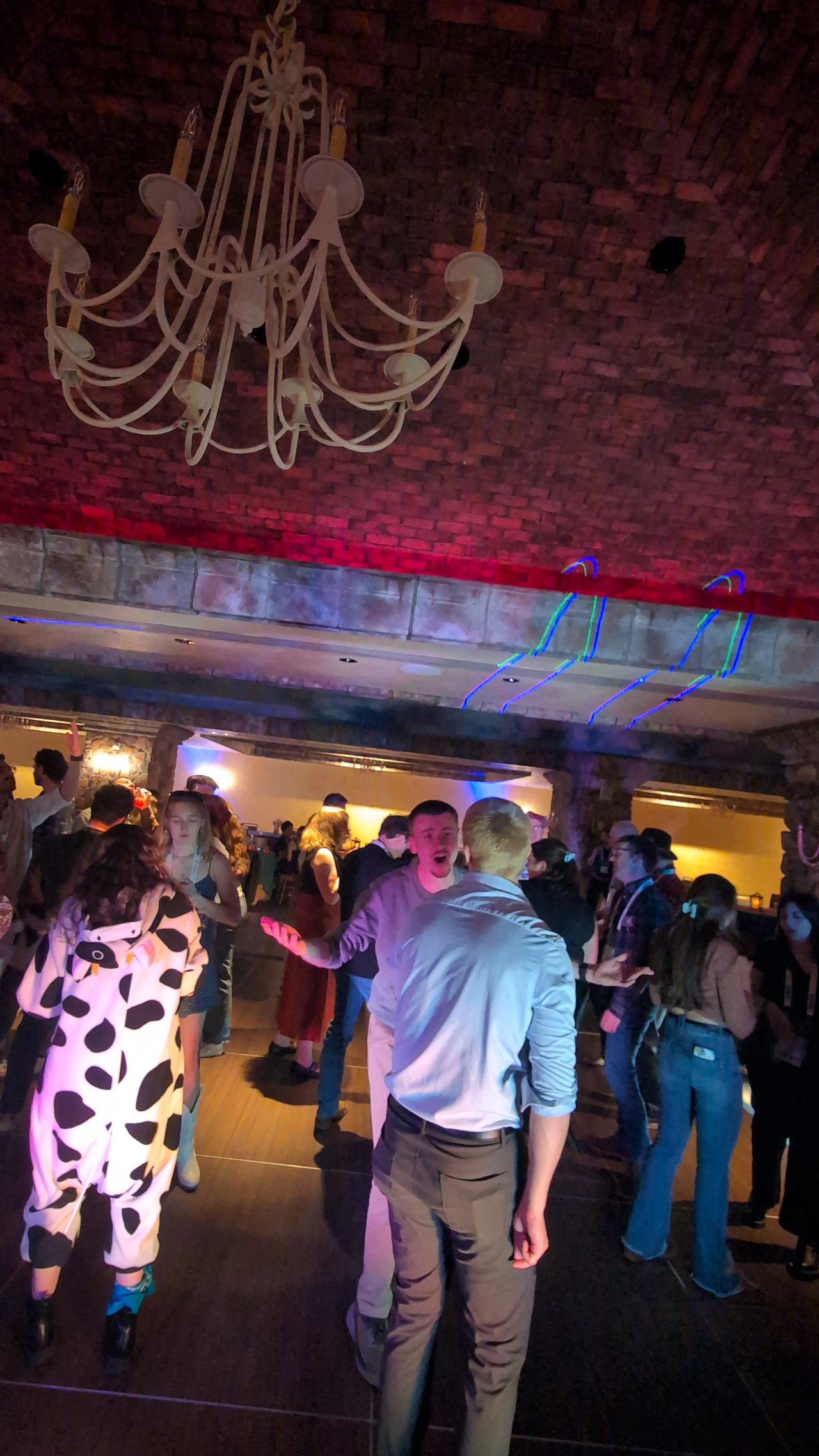 A guest in a cow costume dancing under the chandelier