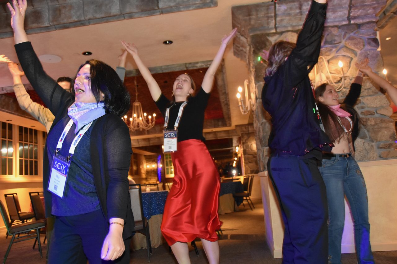 A SciX Gala guest dancing with her arms up on the dance floor