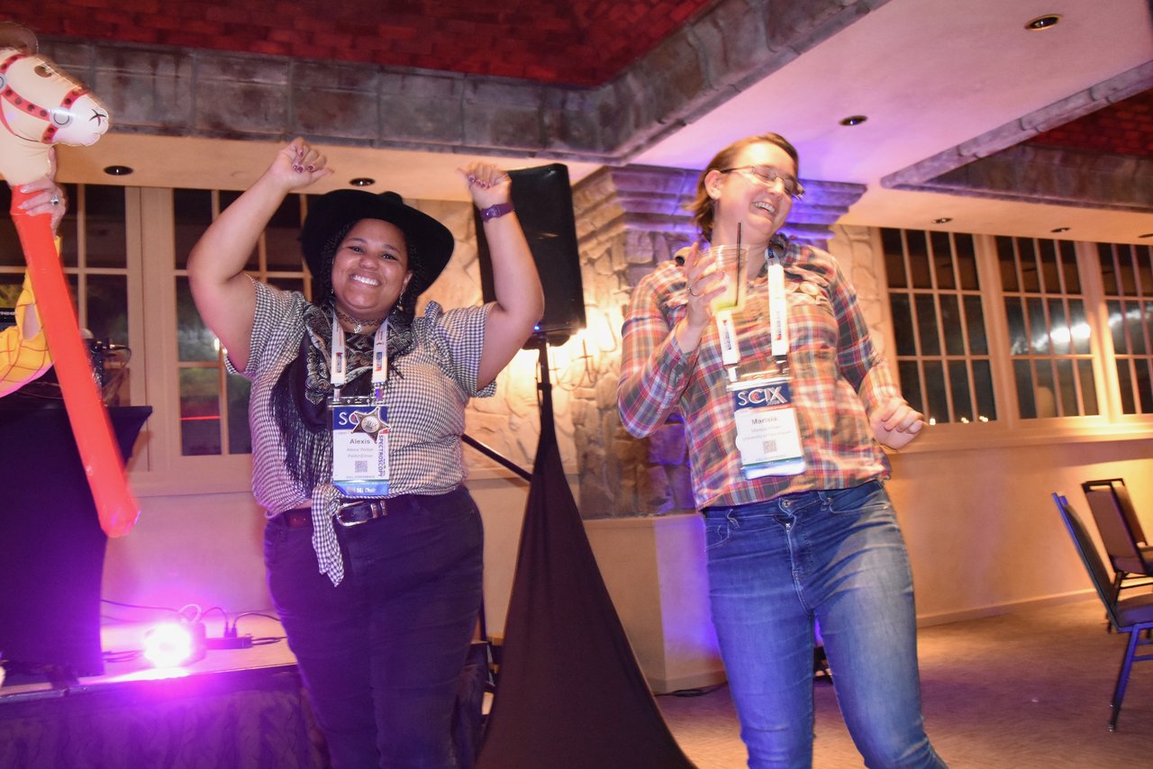 Two SciX Gala guests dancing in front of the stage lights
