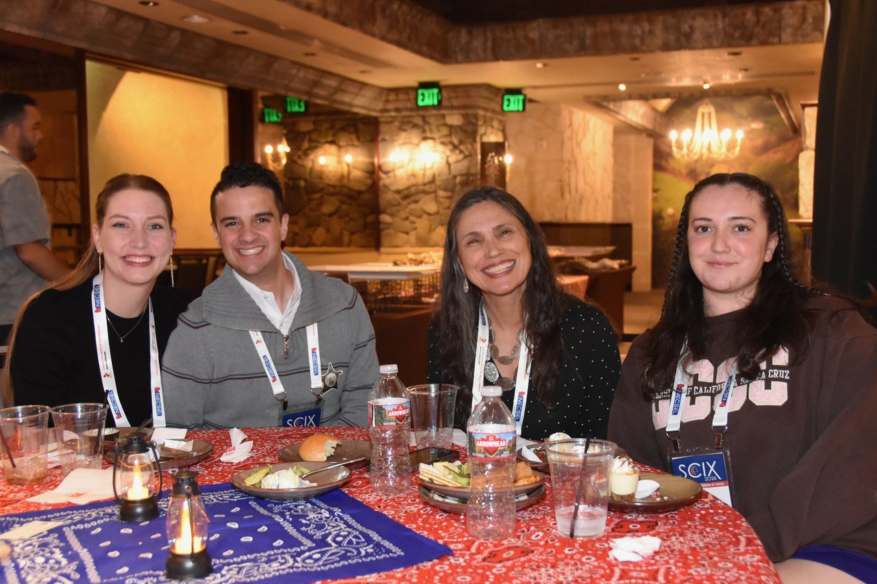 Four SciX Gala guests at a red bandana table with dinner and lanterns