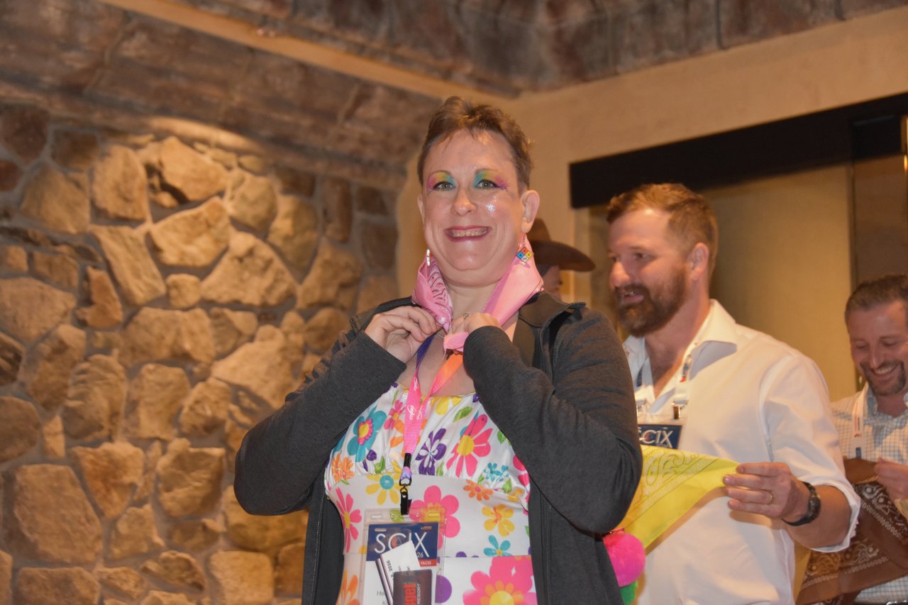 A smiling SciX Gala guest tying on a pink bandana