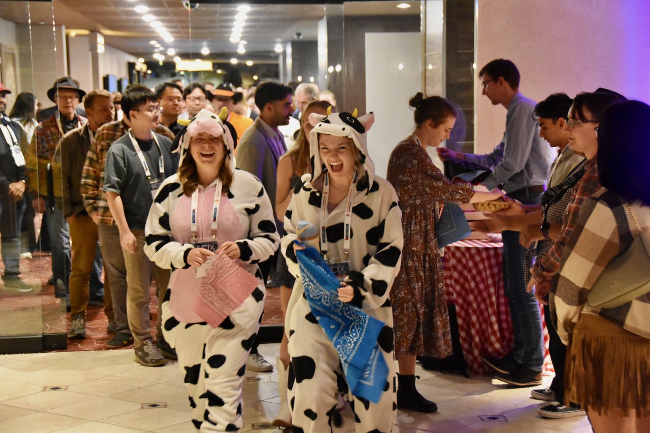 Two SciX Gala guests in cow costumes laughing as they arrive and get their bandanas
