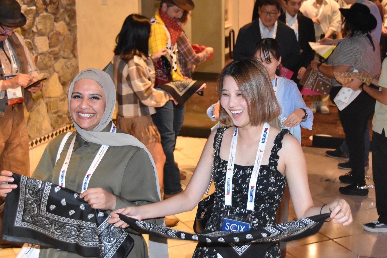 Two SciX Gala guests smiling as they hold up their bandanas