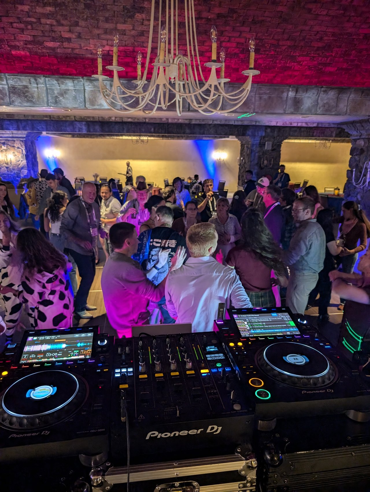 My Pioneer DJ decks lit up at night with a full dance floor behind them at the SciX gala