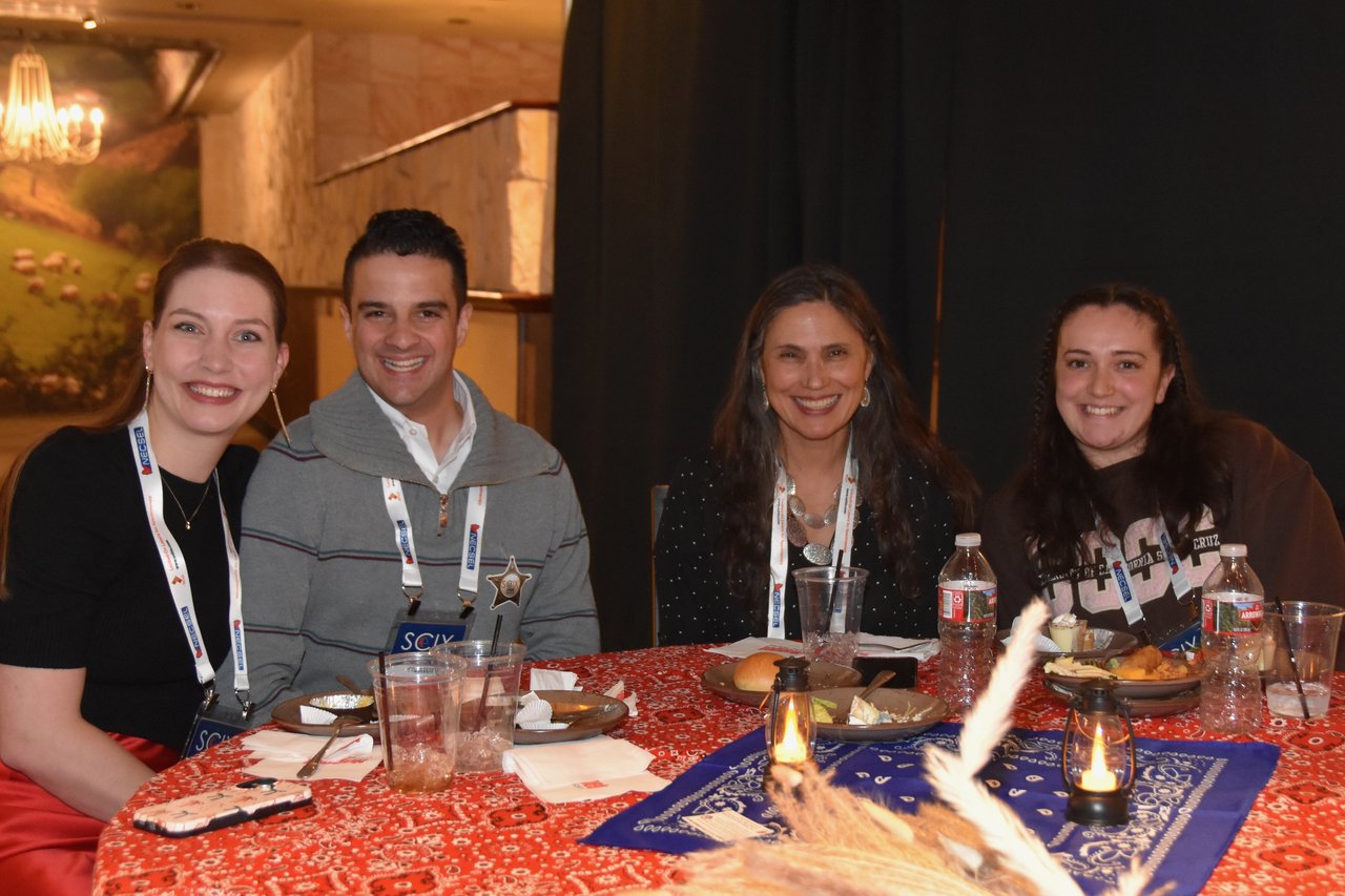 Four guests smiling at a dinner table set with bandanas