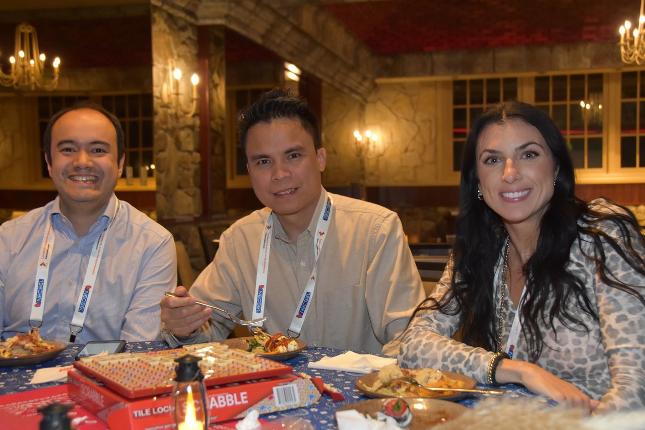 Three SciX Gala guests smiling at a table with a game box