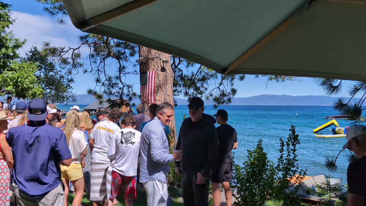 Guests on the lawn at the water's edge under the patio umbrella