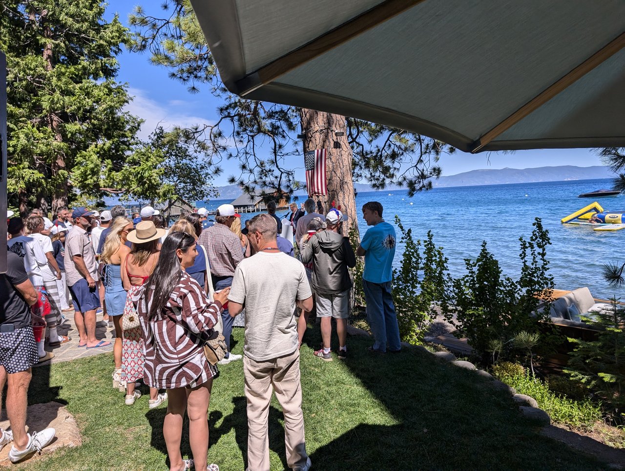 A guest in a striped dress and a guest in a white tee in the crowd by the lake