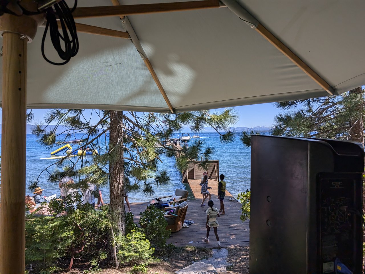 Kids playing on the dock by Lake Tahoe, seen from under the DJ booth umbrella