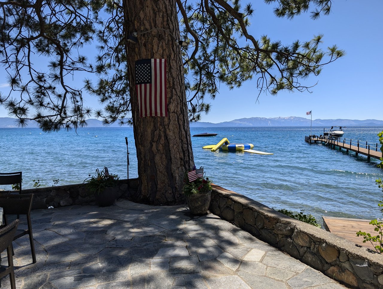 Lake Tahoe from the stone patio before the party, the flag on the pine and the dock beyond