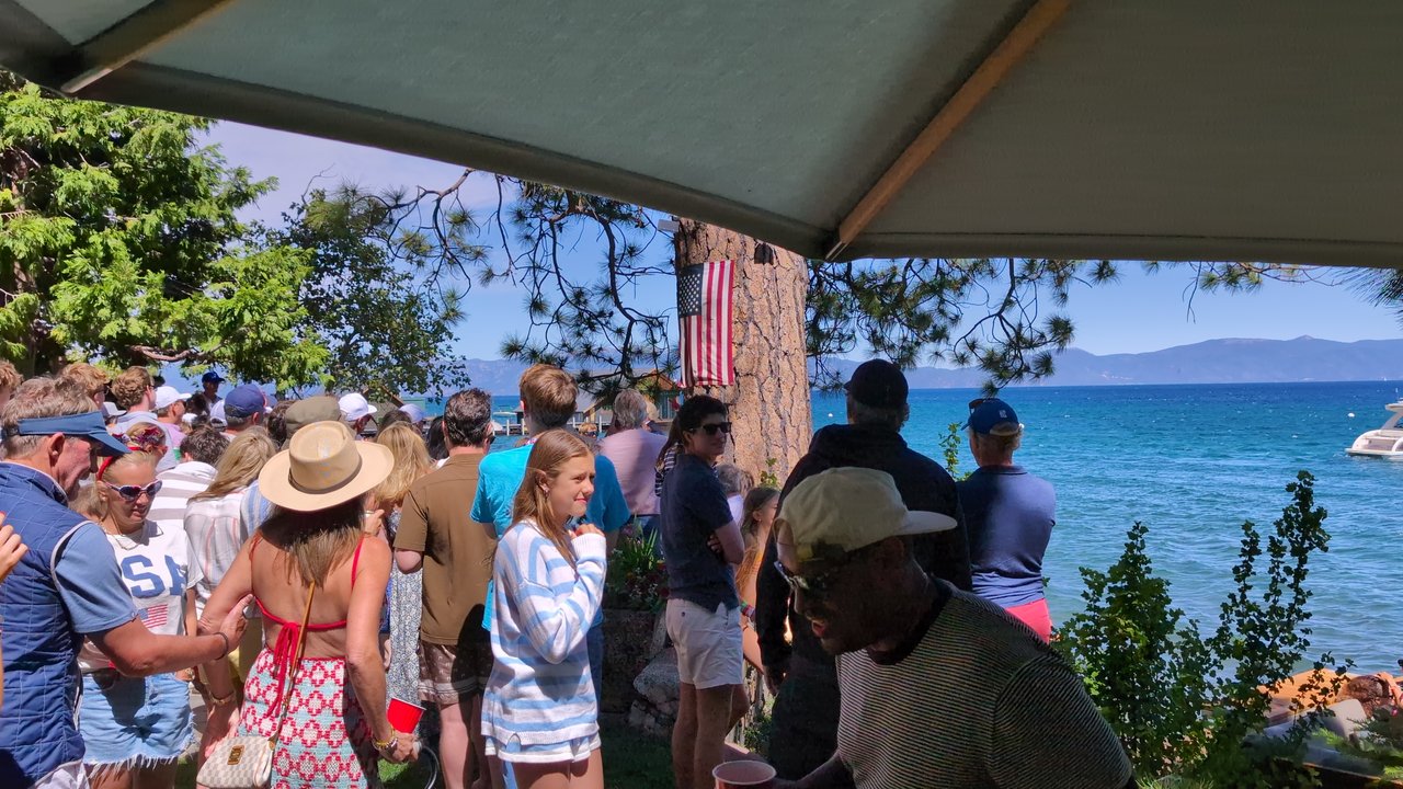 Guests in sun hats and USA shirts filling the lawn by the water