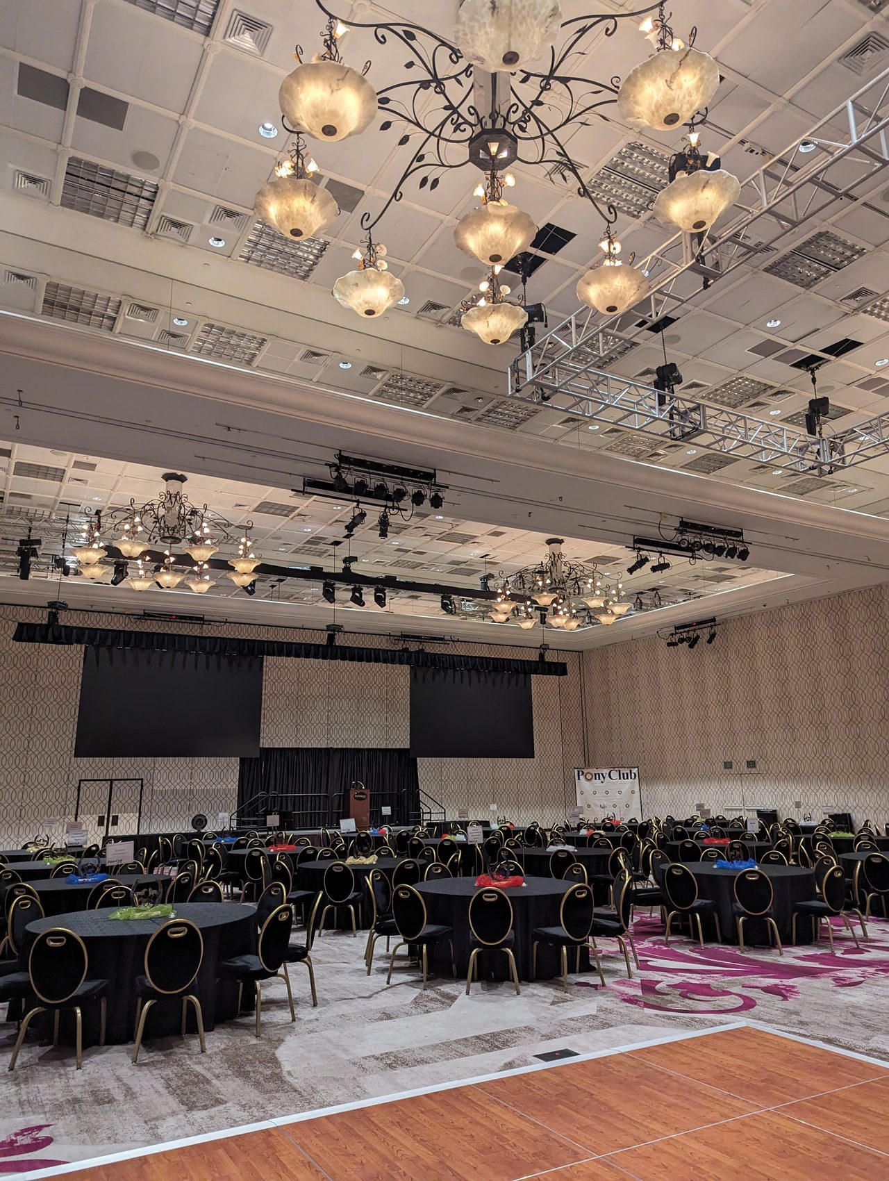 The Peppermill banquet room set for 275 guests under the chandeliers, with the Pony Club banner beside the stage