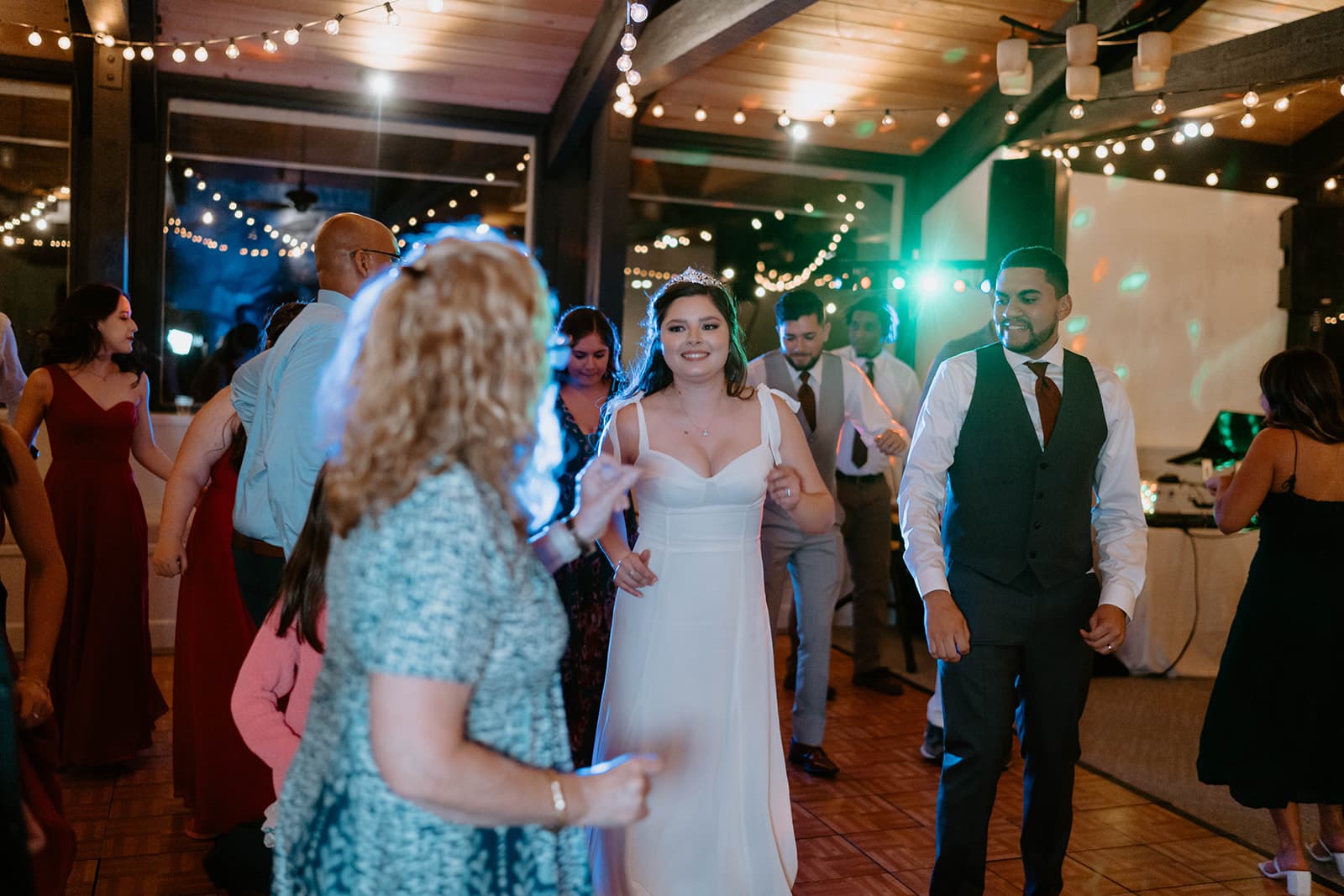 Bride and groom dancing together at wedding reception with string lights - DJs In Reno