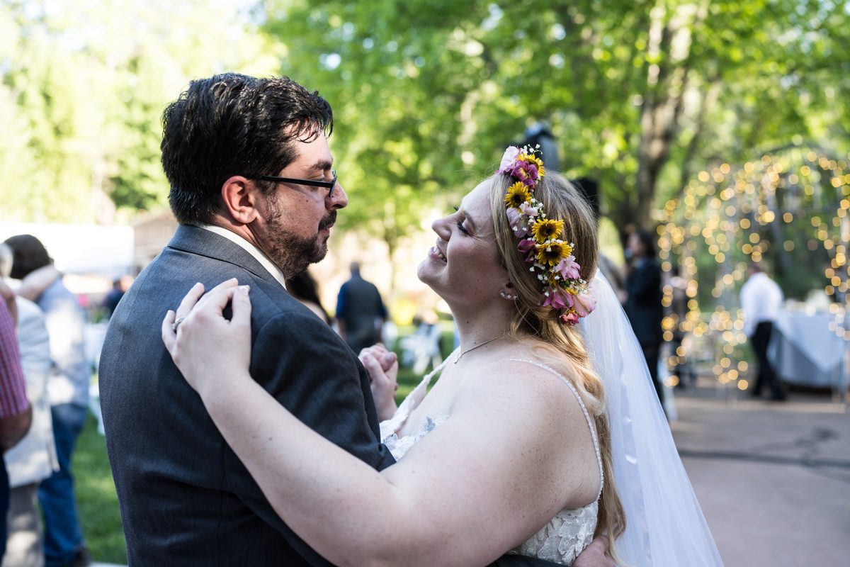 Abney smiles up at Chris during their first dance, with string lights glowing behind them